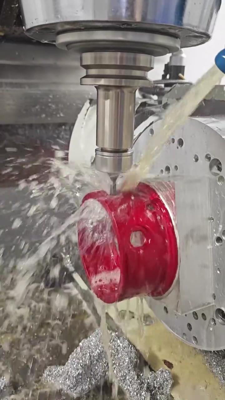 CNC machining process with coolant on red anodized aluminum part